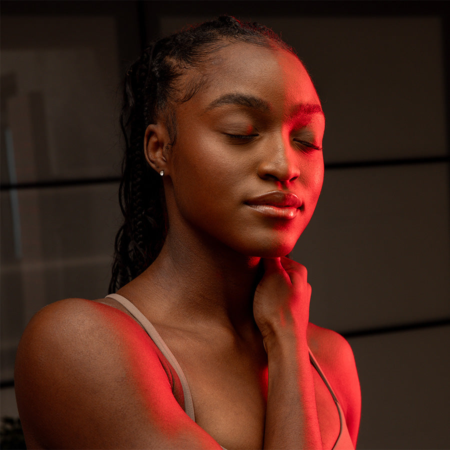 Woman with eyes closed enjoying red light therapy on her neck and face