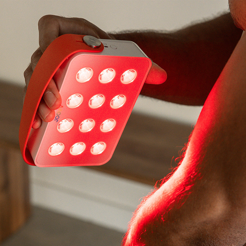 Close up view of a person treating their elbow with Joovv Go red light therapy device